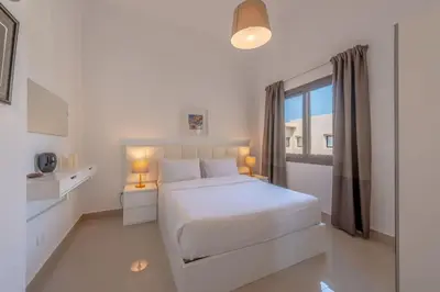 a white bedroom with a white bed and a window at Gcribs apartment pool view in El Gouna