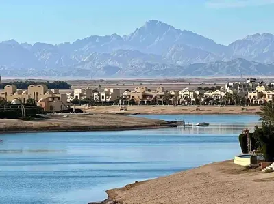 a river with houses and mountains in the background at Artsy 1 BR Apt/ Free Pool & Lagoon Access @ElGouna in Hurghada