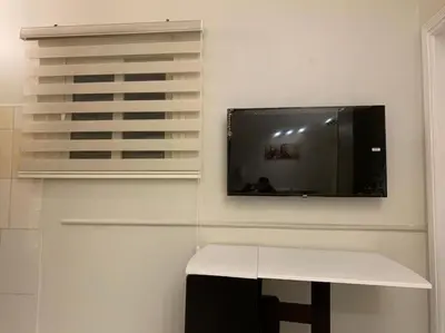 a room with a table and a tv on a wall at Уютная квартира в светлых тонах рядом с легендарной улицей Шератон в центре in Hurghada