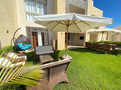 a patio with two chairs and an umbrella at Glamorous 2BR/ Free Beach & Pool Access @ Mangroovy, El Gouna in Hurghada