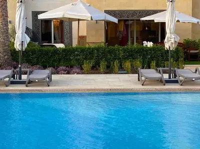 a swimming pool with two chairs and umbrellas at Glamorous 2BR/ Free Beach & Pool Access @ Mangroovy, El Gouna in Hurghada