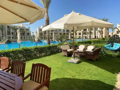 a patio with chairs and umbrellas in front of a resort at Glamorous 2BR/ Free Beach & Pool Access @ Mangroovy, El Gouna in Hurghada