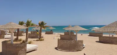 a beach with many straw umbrellas and the ocean at Exceptional Apartment in Soma Bay 4pax in Hurghada