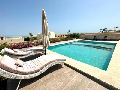 a swimming pool with two lounge chairs and an umbrella at The view compound in Hurghada