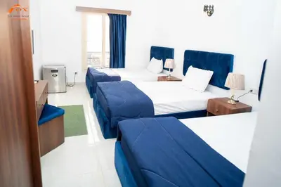 a hotel room with three beds and blue chairs at Fox Resort El Gouna in Hurghada
