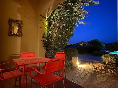 a red table and chairs on a patio at night at Magical 2BR Ground/Free Pool & Lagoon Access @ElGouna in Hurghada