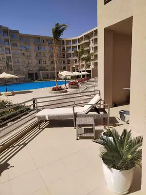a hotel patio with chairs and a swimming pool at Velký apartmán Princess Resort Hurghada in Hurghada