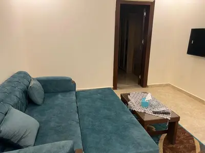 a living room with a blue couch and a table at Mirage bay in Hurghada