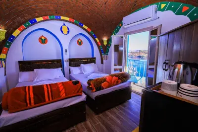 a bedroom with two beds in a room with a window at Nubian Popeye - Roof top - Nile View in Aswan