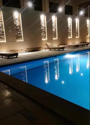 a swimming pool with benches and lights in a building at Hotel Room in Princess Resort With Beach Acces & Free Wi-fi I Near Air port in Hurghada