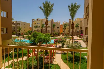 a balcony view of a resort with a pool and palm trees at Go Egypt Apartments Inside Karma Beach Resort North Al Ahiaa , Hurghada in Hurghada