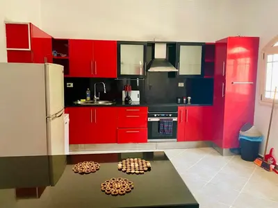 a kitchen with red cabinets and a table in it at villa 5 in magawish in Hurghada