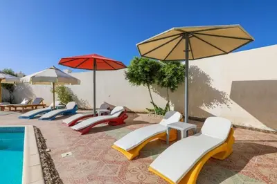 a group of chairs and umbrellas next to a pool at La BONITA FLAT in Hurghada