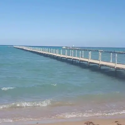 a pier stretches out into the ocean with a beach at Fox Beach Stay in Hurghada