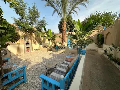 a group of blue benches in a yard with palm trees at Villa Rebecca Professor's paradise in Luxor