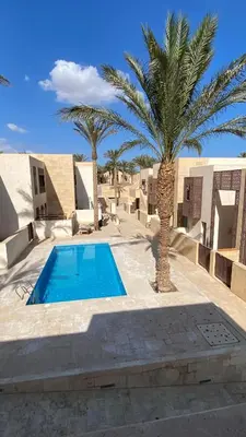 a resort with a swimming pool and palm trees at Bright & Lovely 2 Beds Apartment in Scarab Club, El Gouna in Hurghada