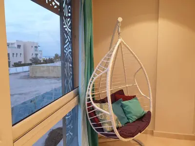 a hanging hammock chair on a balcony with a window at Mangroovy- 1BR Sea Breeze Back Sea view in Hurghada
