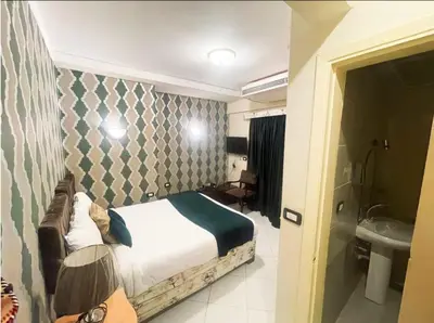 a bedroom with a bed and a bathroom with a sink at فندق جولدن صن العروسه طريق الشيراتون السقالة ميدان محافظة البحر الأحمر 84511 مصر in Hurghada