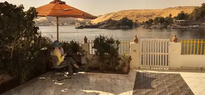 a person sitting in a chair under an umbrella at Esmerada in Aswan