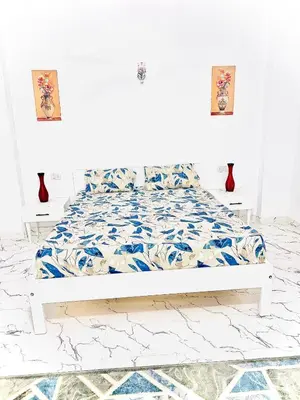 a white bedroom with a bed with blue and white sheets at Muhammad Ali House in Luxor