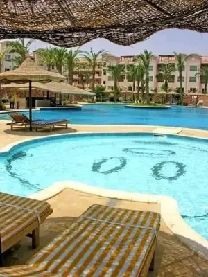 a large swimming pool with benches in a resort at Sunset pearl, Sahl Hashish in Hurghada