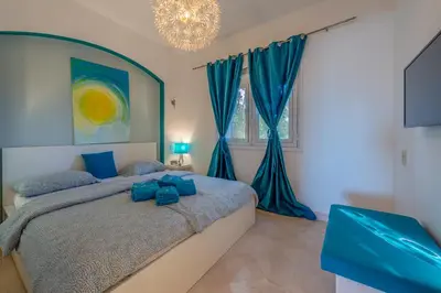 a bedroom with a bed with blue curtains and a chandelier at Special style apartment with pool at lagoon in Hurghada