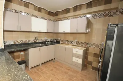a kitchen with white cabinets and tile walls at Ramsses Palace in Luxor