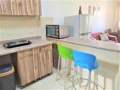 a kitchen with a counter with two chairs and a microwave at 2 bedrooms cozy flat at makadi heights in Hurghada