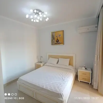a bedroom with a white bed and a chandelier at Private 3 bdrm apartment at ElKarma Aqua Beach Reaort in Hurghada