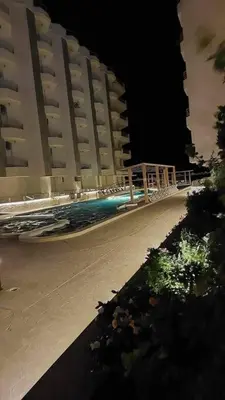 a swimming pool at night with tall buildings at La Quinta Resort Hurghada in Hurghada