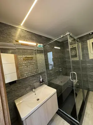 a bathroom with a sink and a glass shower at Relaxation, fresh air, and a direct view of the Nile in Naj‘ al ‘Amrāb