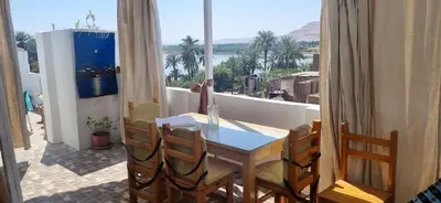 a table and chairs on a balcony with a view of the water at Abo Hisham Nile Flat in Luxor