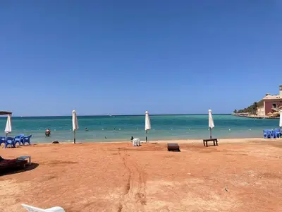 a beach with umbrellas and people in the water at Villa 2 apartment 2 village veiw infront of Palma de Meritee in Hurghada