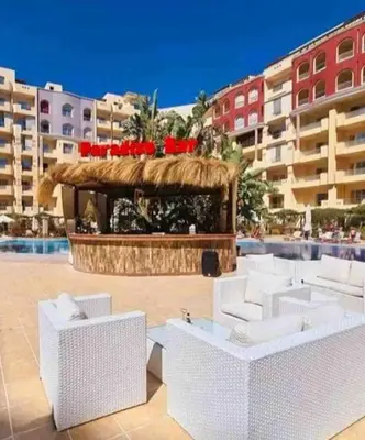 a pool with white chairs and a gazebo in a resort at Studio Pool view with balcony Florenza Hurghada in Hurghada