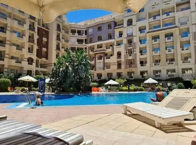 a large building with a swimming pool in front of it at Studio Pool view with balcony Florenza Hurghada in Hurghada