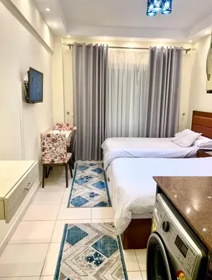 a hotel room with two beds and a chair at Studio Pool view with balcony Florenza Hurghada in Hurghada