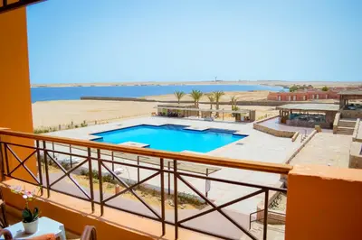 a balcony with a swimming pool and the ocean at Viva Blue Resort and Diving Sharm El Naga (Adults Only) in Hurghada
