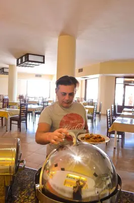 a man standing in a restaurant with a plate of food at Viva Blue Resort and Diving Sharm El Naga (Adults Only) in Hurghada