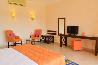 a bedroom with a bed and a television and chairs at Viva Blue Resort and Diving Sharm El Naga (Adults Only) in Hurghada