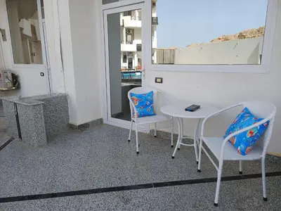 a patio with two chairs and a table and a window at Pool view studio with terrace in Hurghada