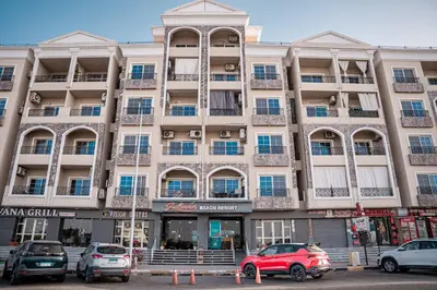a large building with cars parked in front of it at Juliana Beach Hurghada in Hurghada