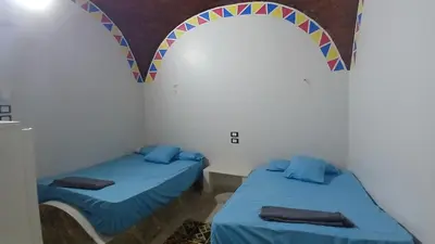 two beds in a room with a rainbow decoration on the wall at Ezzo Nubian guest house in Aswan