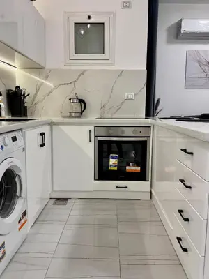 a kitchen with white cabinets and a washer and dryer at Marina View Apartment in Hurghada