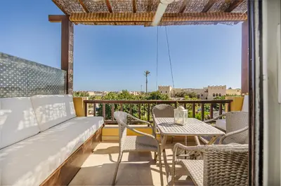 a balcony with a couch and a table and chairs at Wonderful apartment with prime location & pool in Hurghada