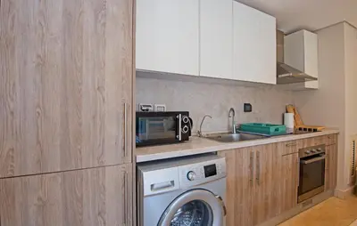 a kitchen with a washing machine and a microwave at Ollystays Mangroovy 2 BR Beach and Pool Free access in Hurghada