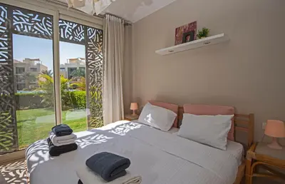 a bedroom with a bed and a large window at Ollystays Mangroovy 2 BR Beach and Pool Free access in Hurghada
