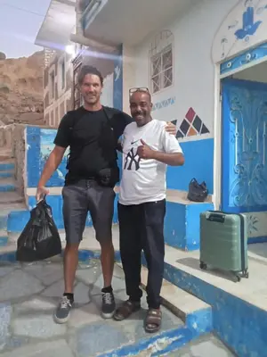 two men standing in front of a blue building at Bakar House in Aswan