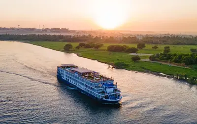 a cruise ship traveling down a river at sunset at 5 Days / 4 Nights Cruise Trip from Luxor to Aswan With all Visits Every Saturday, Monday and Thursday in Luxor