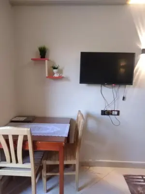 a dining room table with chairs and a television on a wall at Florenza khamsin compound unit g4 in Hurghada