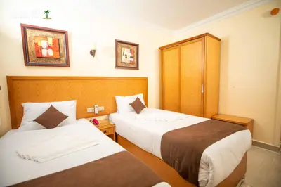 a hotel room with two beds and a cabinet at Palm Inn Hotel Hurghada in Hurghada